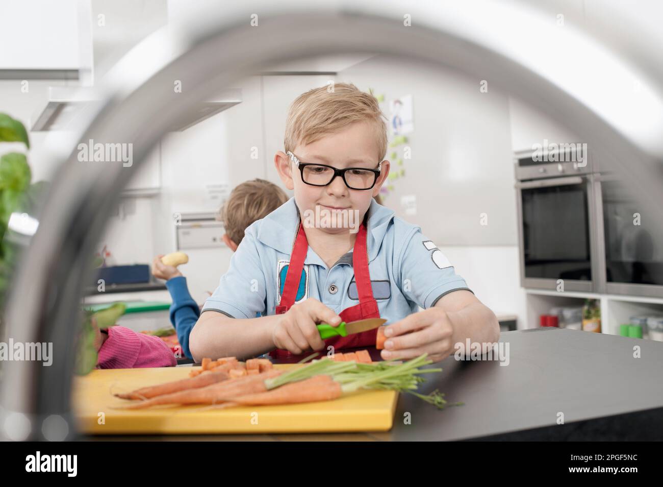 Due scolari che tagliano verdure in classe economica domestica, Baviera, Germania Foto Stock