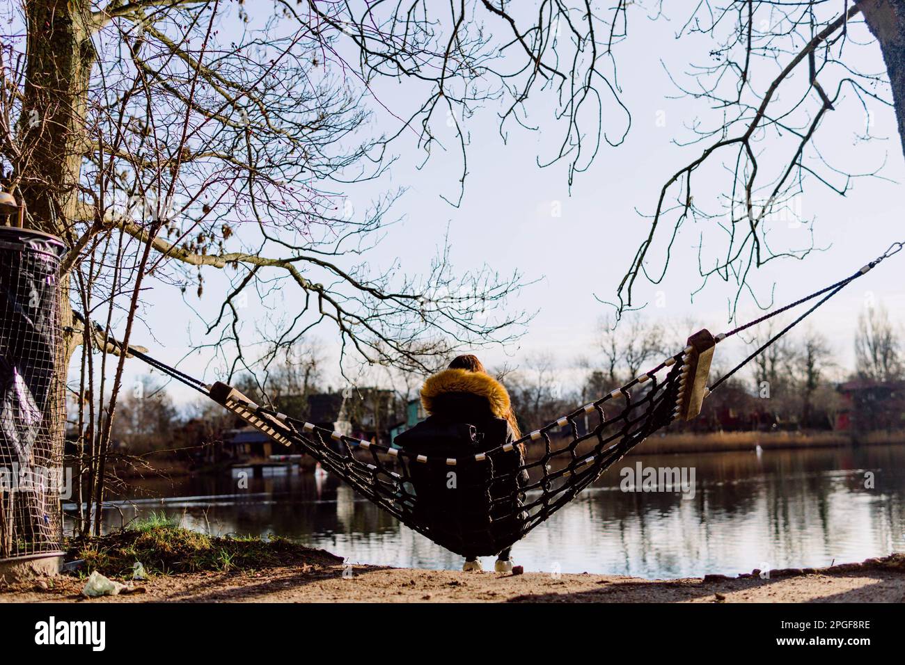 persona seduta in amaca appesa su due alberi contro il fiume Foto Stock