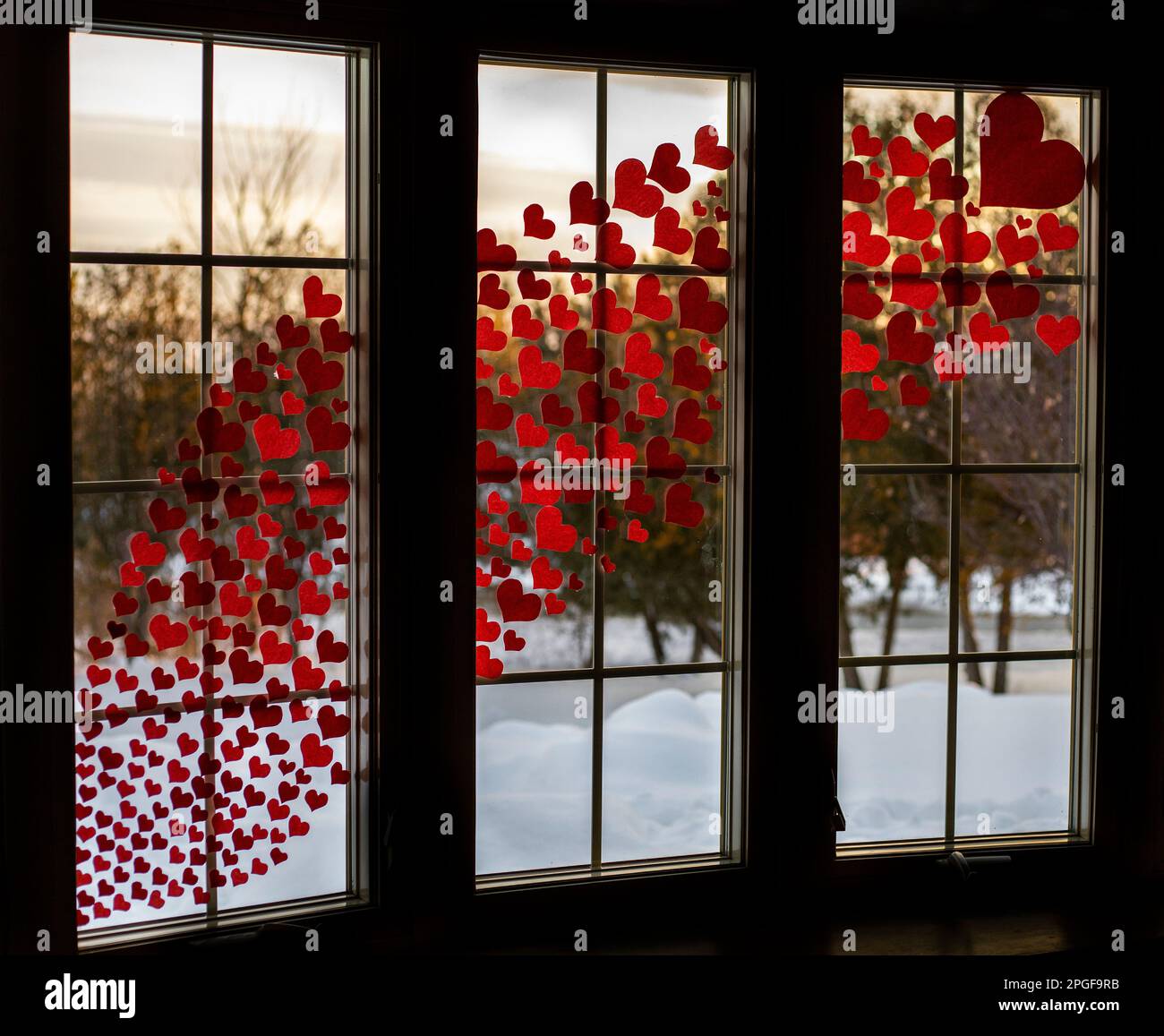 Amate i cuori in finestra con la neve fuori Foto Stock