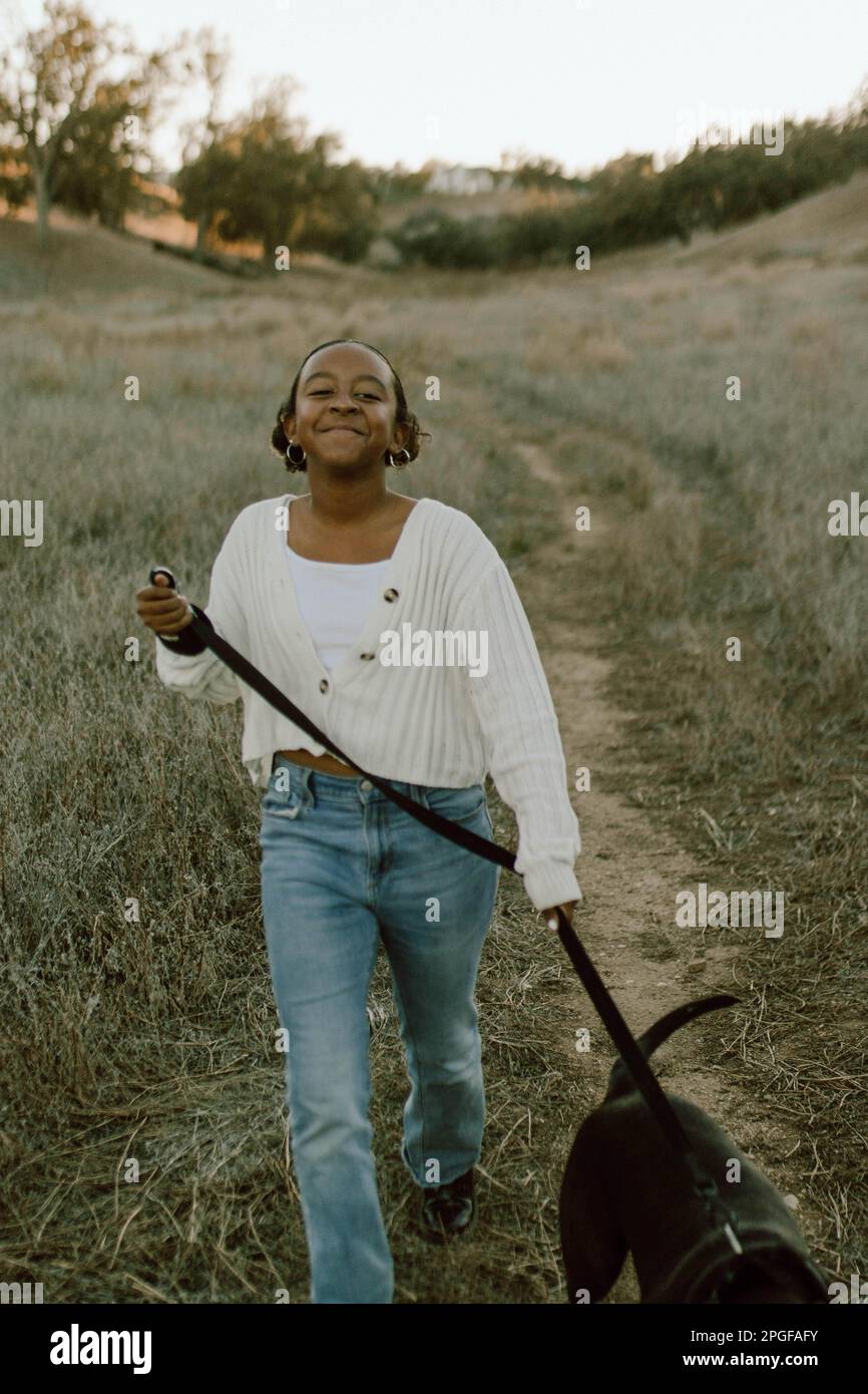 ragazza che corre attraverso il campo con il suo cane Foto Stock