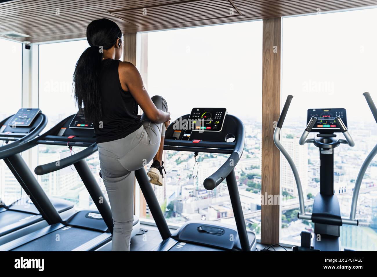 donna africana in palestra stretching sul tapis roulant Foto Stock
