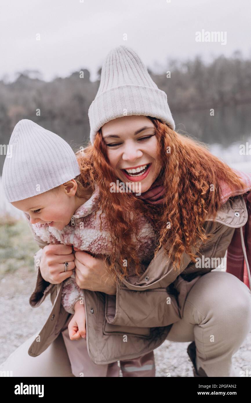 Una donna gioca con una bambina nel parco, sorride e la abbraccia Foto Stock