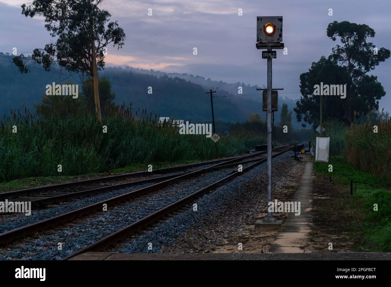 Paesaggio con semaforo ferroviario e sentieri contro colline in nebbia Foto Stock
