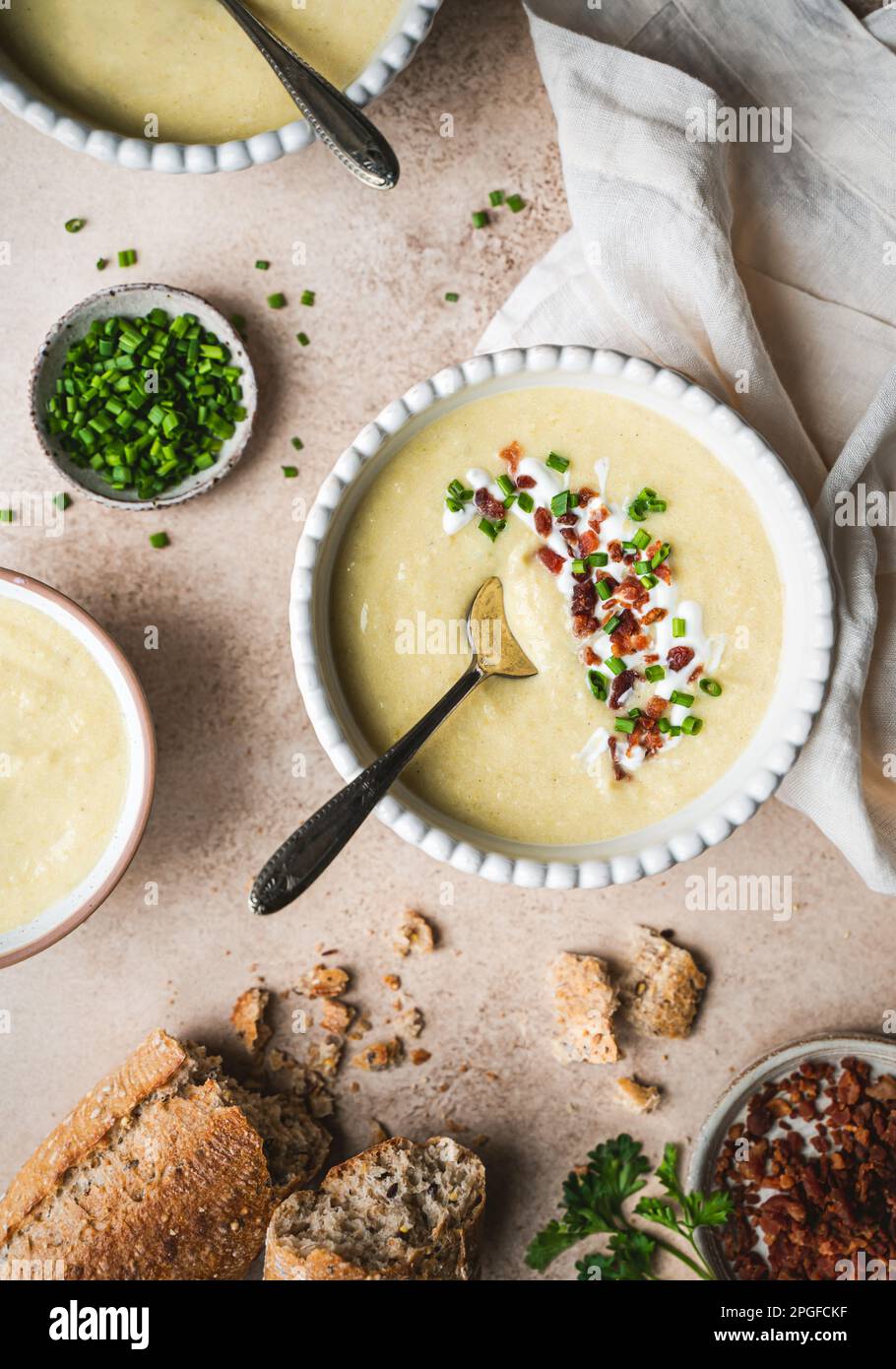 Ciotole di zuppa di porro di patate e pane su sfondo beige dall'alto. Foto Stock