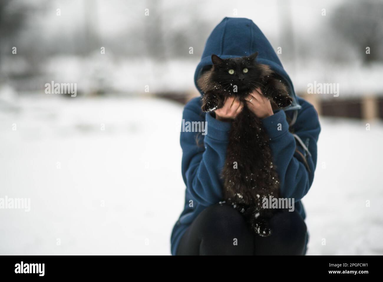 Ragazza che tiene gatto nero nella neve Foto Stock