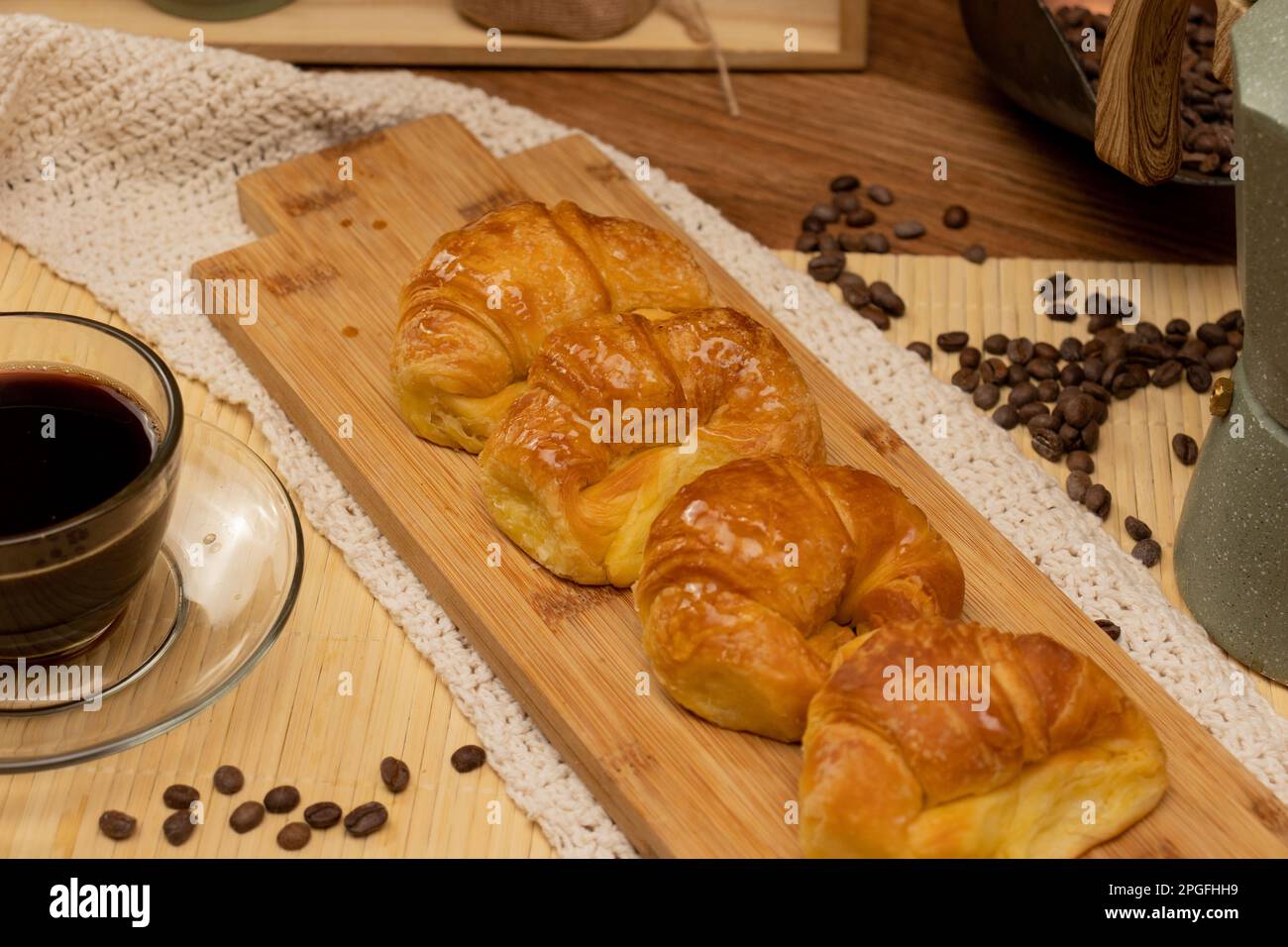Colazione argentina. Croissant con una tazza di caffè e chicchi di caffè nella natura morta. Foto Stock