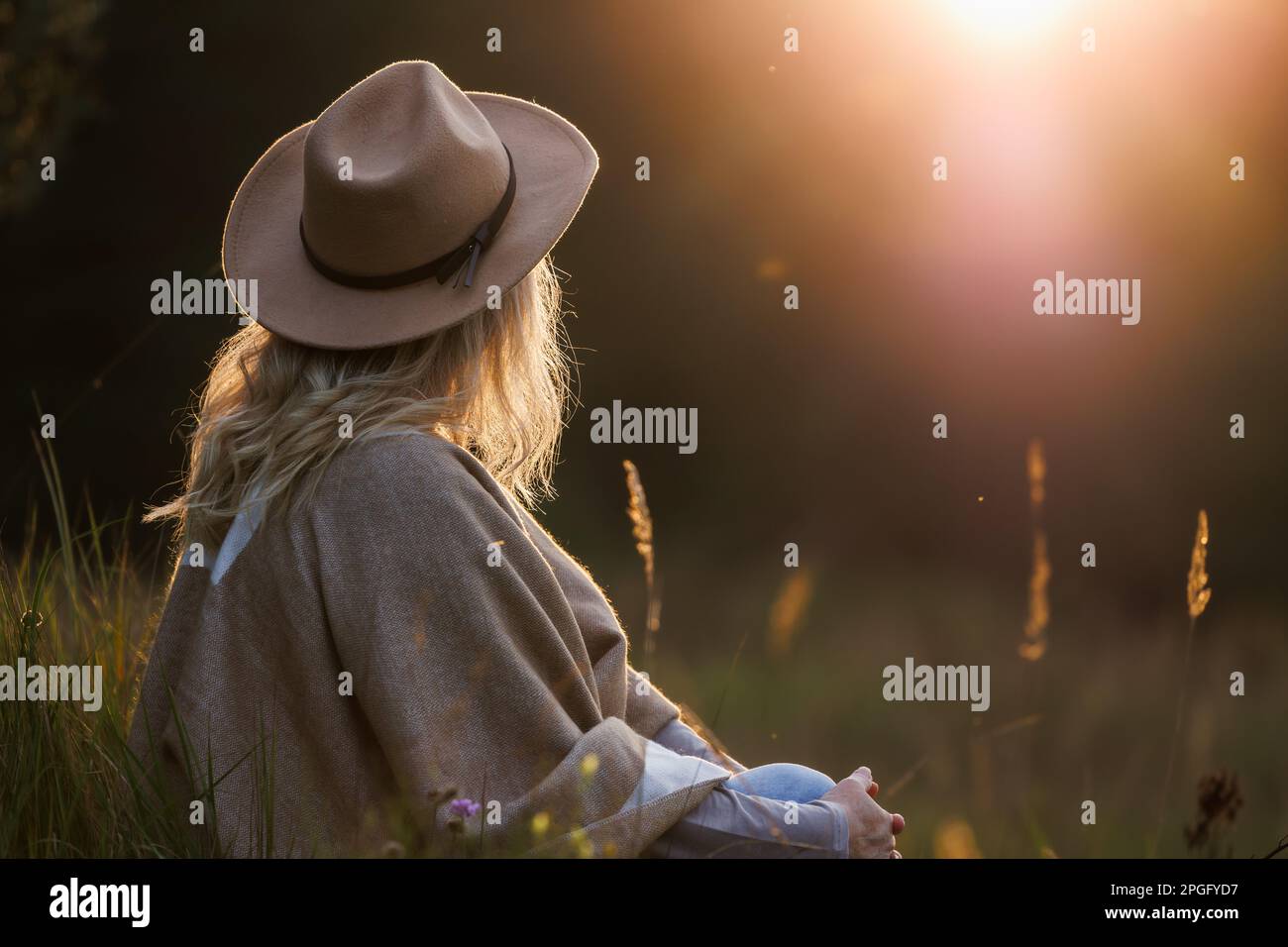 Donna che gode l'armonia e l'equilibrio di vita con la natura durante il tramonto. Relax all'aperto per una buona salute mentale e migliorare la consapevolezza Foto Stock