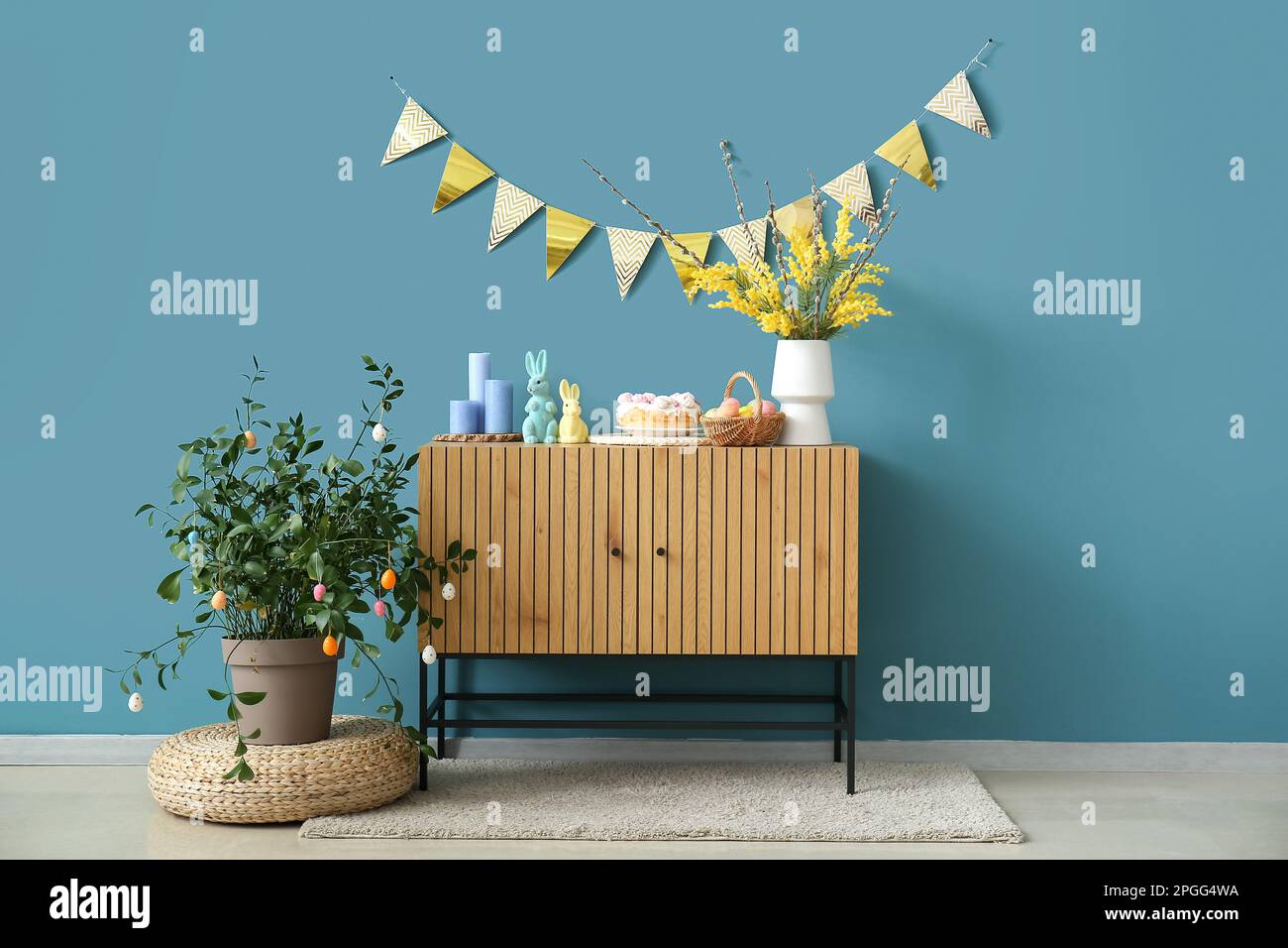 Decorazioni pasquali su armadio in legno vicino alle pareti blu Foto Stock
