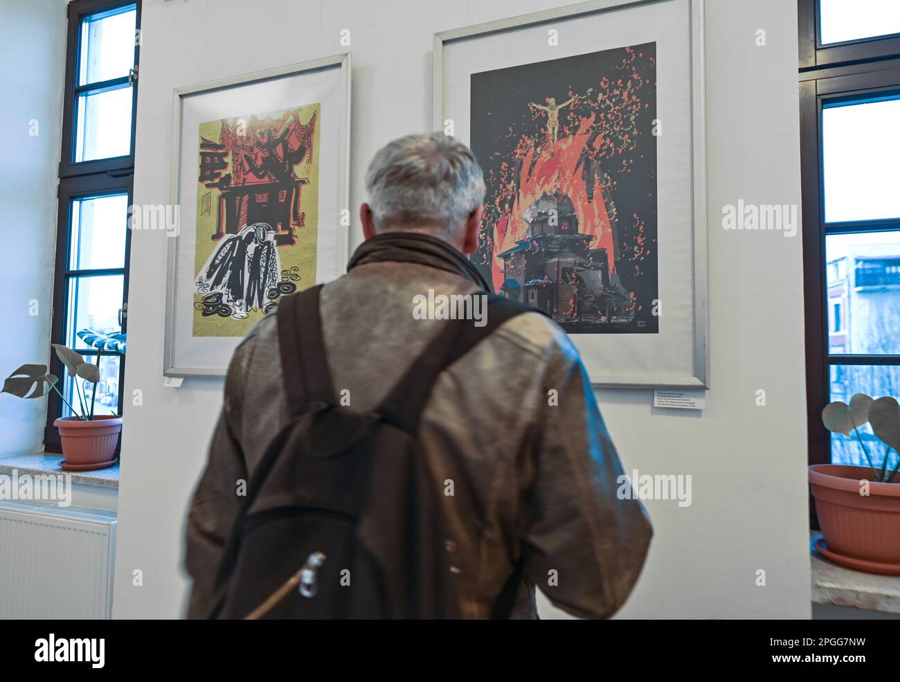 CRACOVIA, POLONIA - 22 MARZO 2023: Un visitatore sta guardando le opere di Inna Linyova, alla mostra di poster "Save the Future", aperta presso la Biblioteca Provinciale pubblica, il 22 marzo 2023, a Cracovia, Polonia. Inna Linyova, pittore ucraino, grafico con sede negli Stati Uniti dal 2003, crea composizioni all'avanguardia. Il dolore dell'artista per la situazione della sua patria durante la guerra si riflette nel suo lavoro, utilizzando il linguaggio dei manifesti per attirare l'attenzione sull'incubo che è venuto in Ucraina dalla Russia. Uno dei suoi poster, "Ucraina incinta", raffigura la patria come una donna incinta protetaria Foto Stock