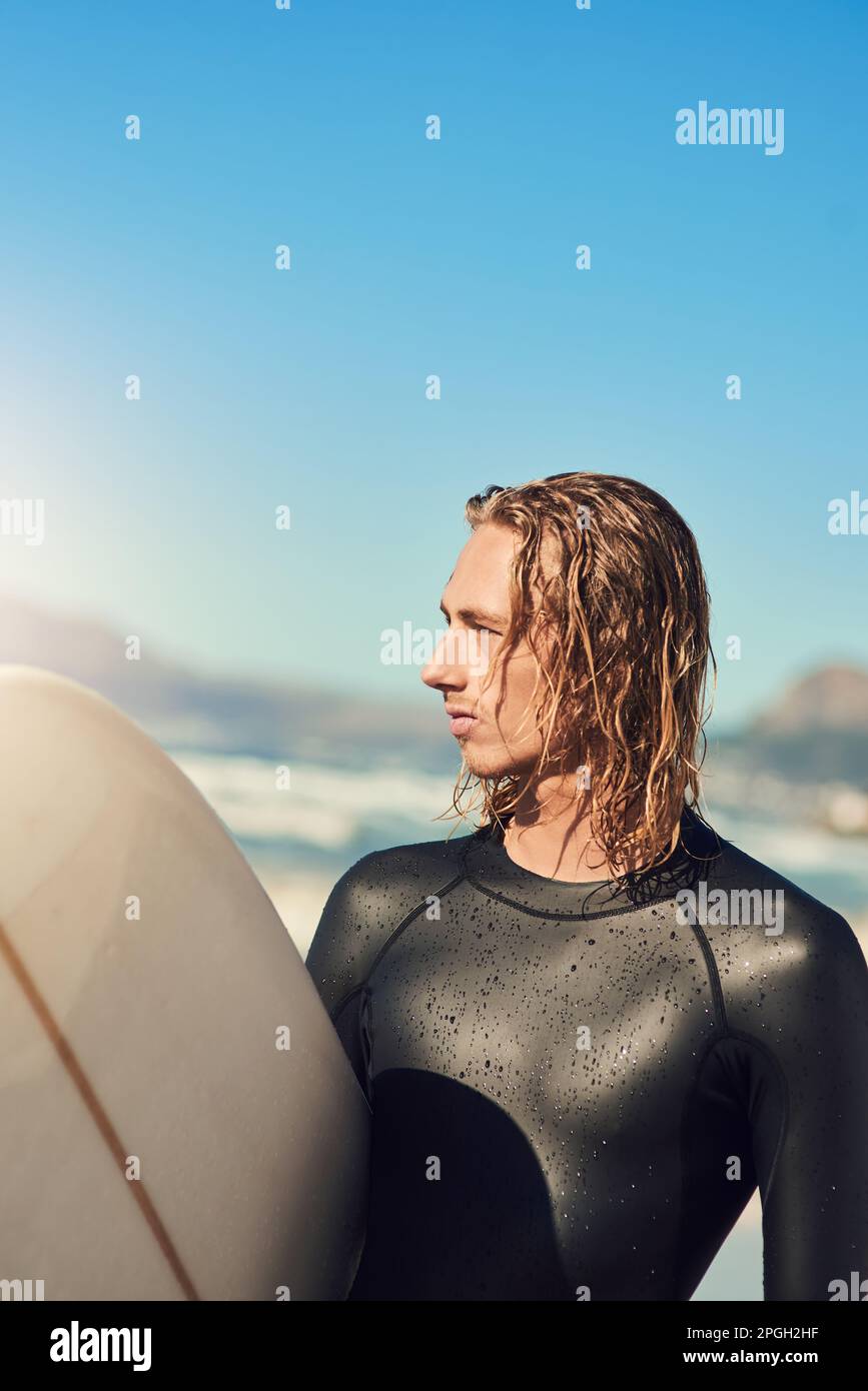 La navigazione mi permette di essere più avventuroso. un bel giovane uomo in spiaggia con la sua tavola da surf. Foto Stock