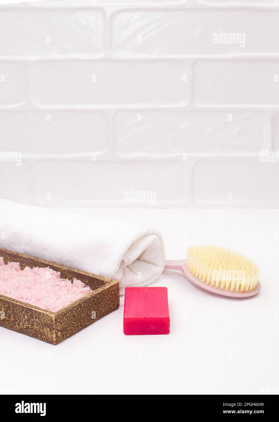 Asciugamano, spazzola per il corpo, sapone, sale marino su sfondo bianco del bagno. Concetto di auto-cura, vasca da bagno, spa. Spazio di copia Foto Stock