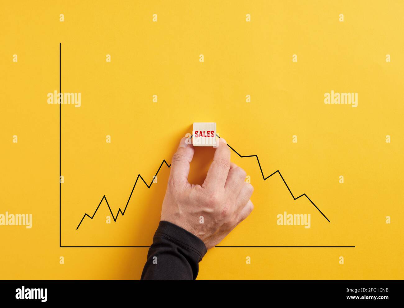 Previsione delle vendite di prodotti o servizi aziendali. Punto di saturazione delle vendite. La mano tiene il cubo di legno con le vendite di parola con un crescente e declinante Foto Stock