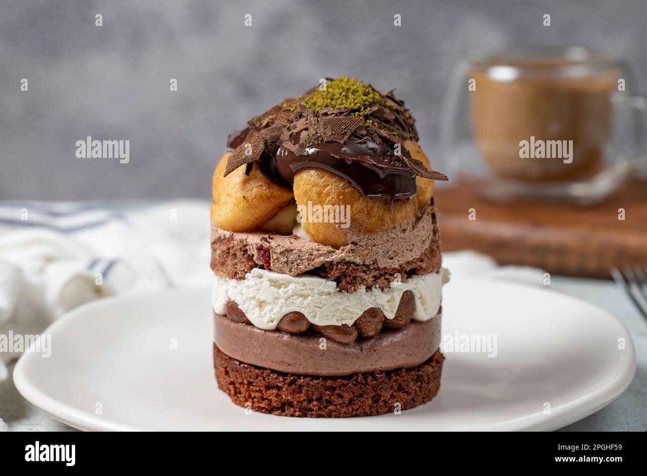 Torta a strati di profiteroles. Panna montata, cioccolato e torta al pistacchio. Primo piano. Foto Stock