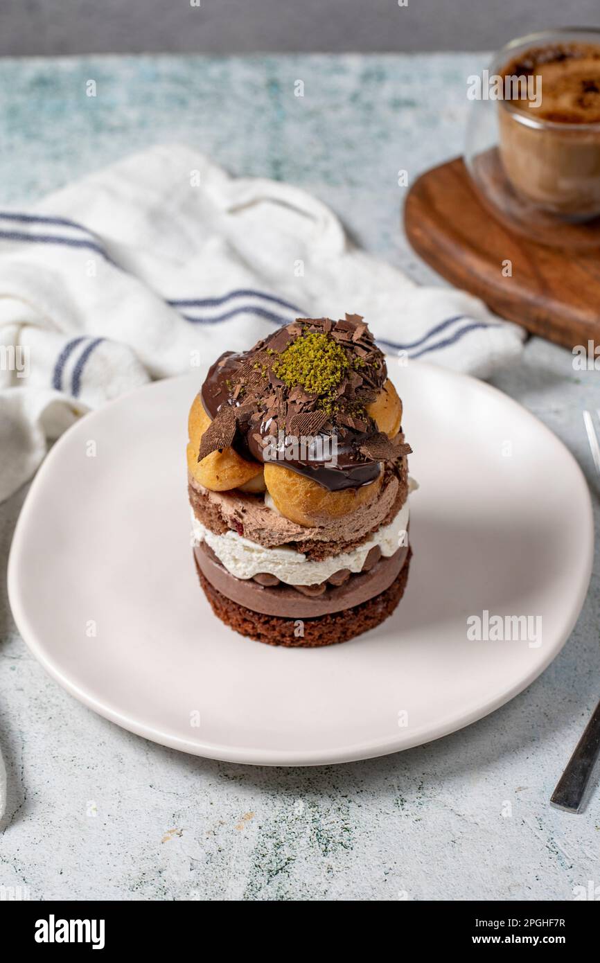 Torta a strati di profiteroles. Panna montata, cioccolato e torta al pistacchio. Foto Stock