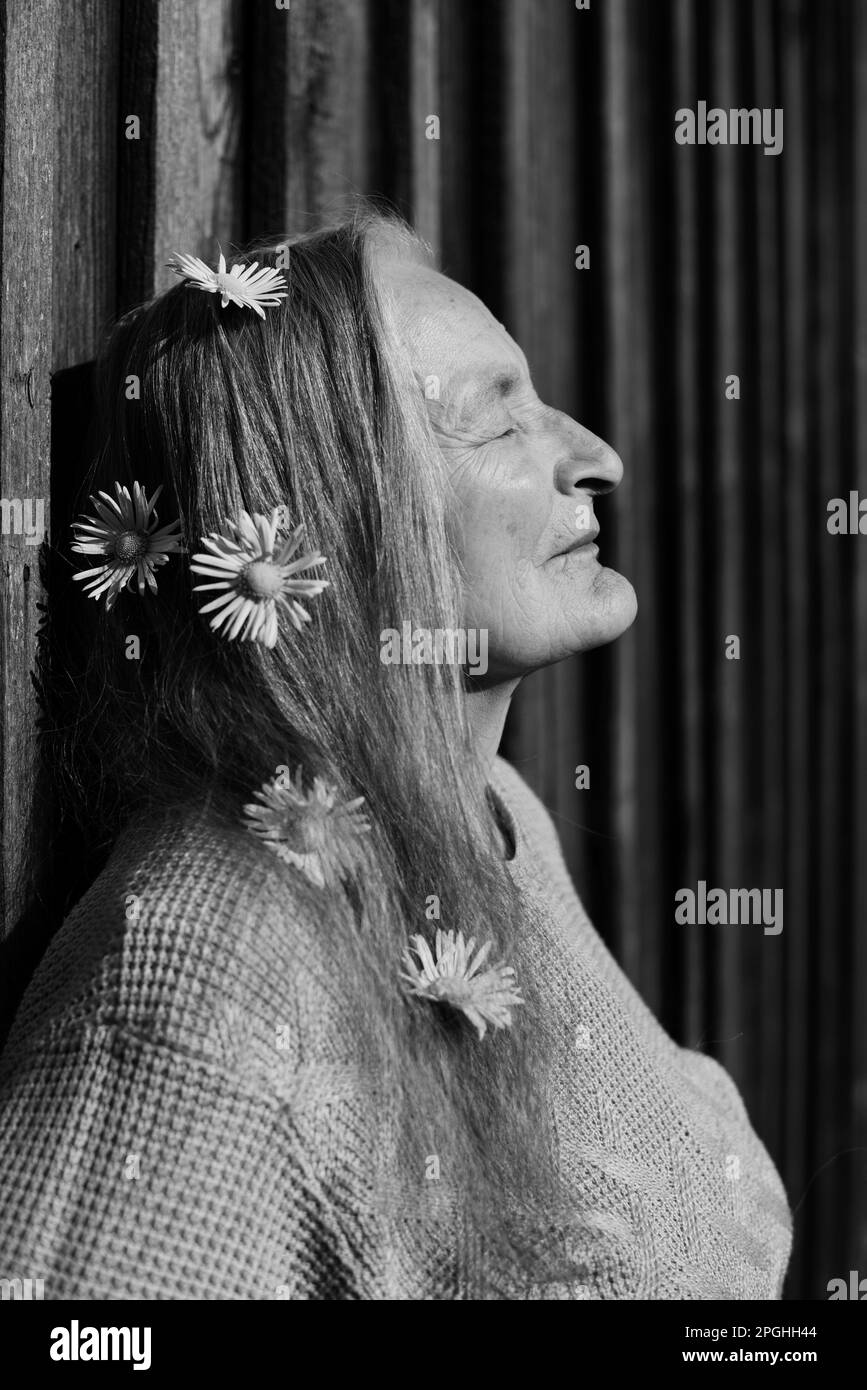 Donne anziane con fiori nei capelli davanti al sole Foto Stock
