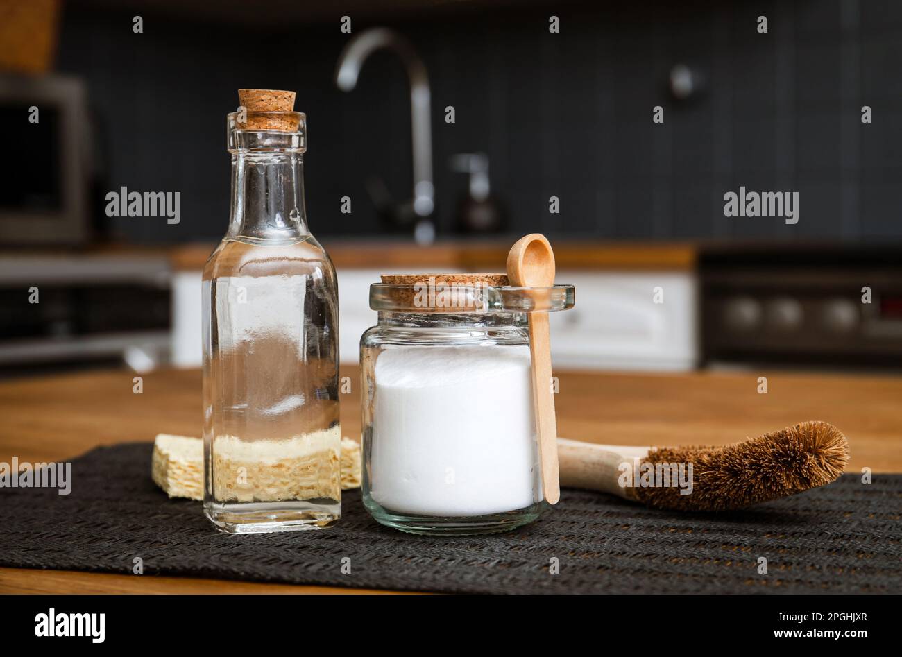 Utilizzando bicarbonato di sodio bicarbonato di sodio e aceto bianco per la pulizia cucina casa concetto. Aceto bianco in bottiglia di vetro e bicarbonato in vaso di vetro. Foto Stock