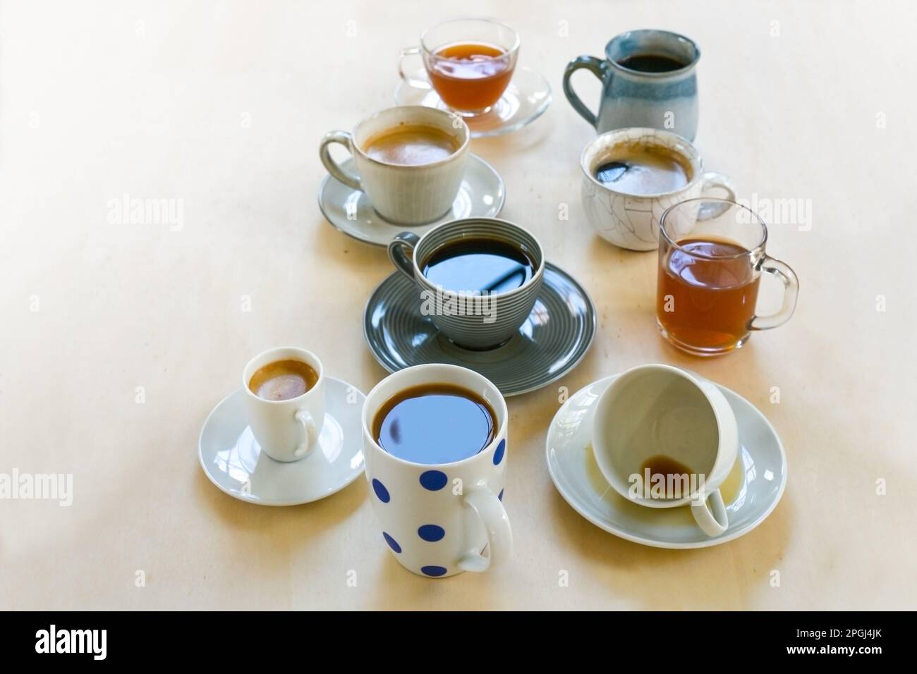 Tazze e tazze diverse di ceramica, porcellana, vetro con caffè e tè bevande su un tavolo di legno chiaro, spazio copia, focus selezionato, profondità stretta o Foto Stock