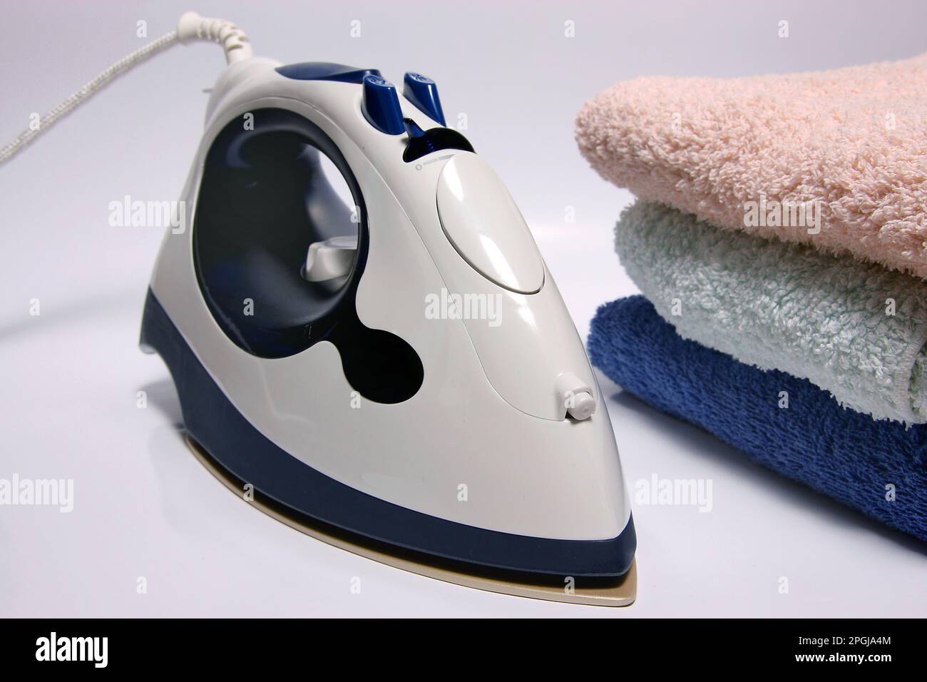 ferro da stiro a vapore accanto ad asciugamani piegati, lavori di casa Foto Stock