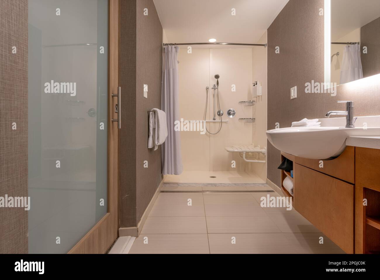 Bagno con doccia accessibile con sedia a rotelle, pavimento piastrellato e pareti. Foto Stock