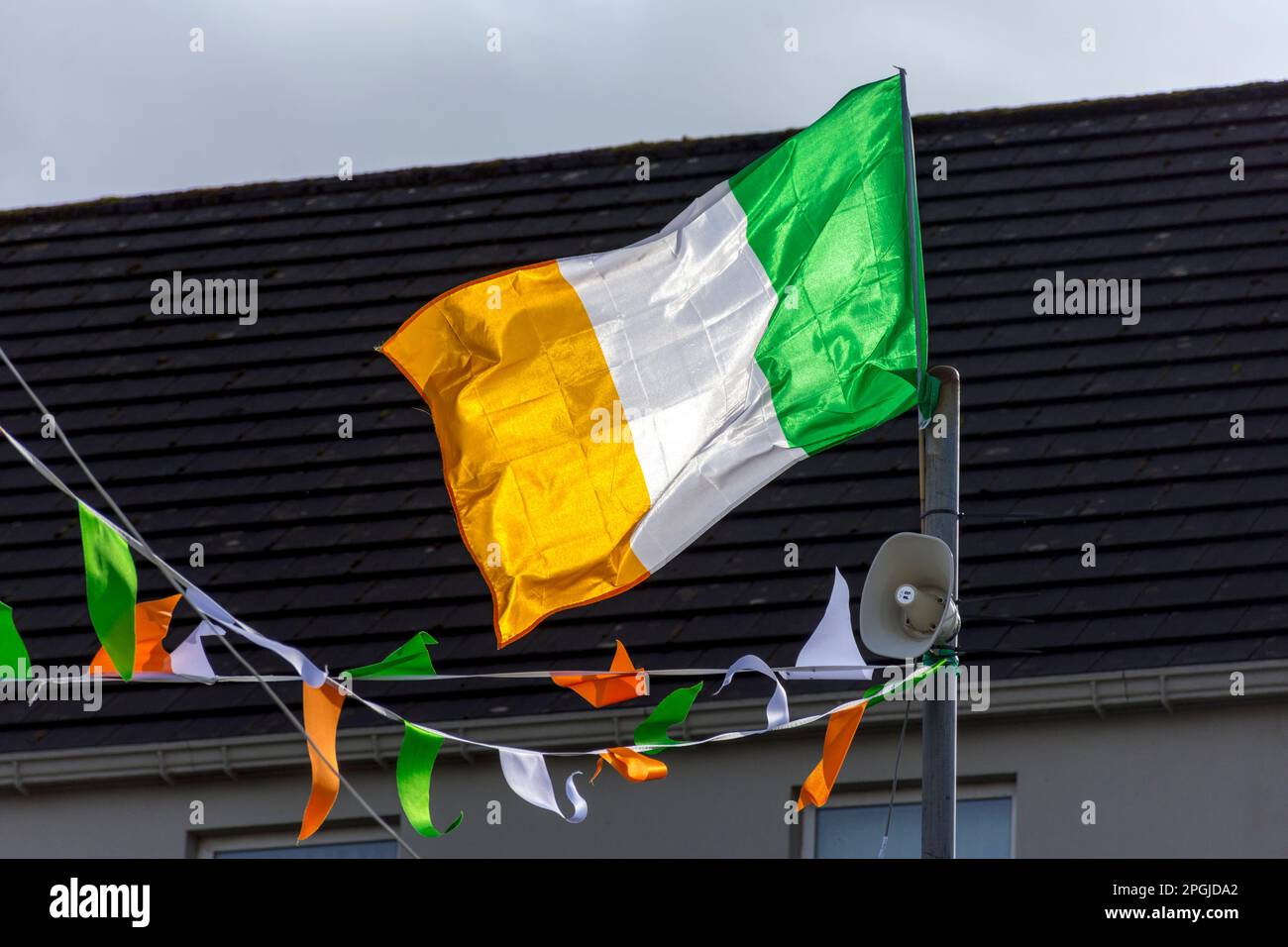 Bandiera nazionale irlandese tricolore e sistema di comunicazione al pubblico per St.. Parata del giorno di Patrizio ad Ardara, Contea di Donegal, Irlanda. Foto Stock
