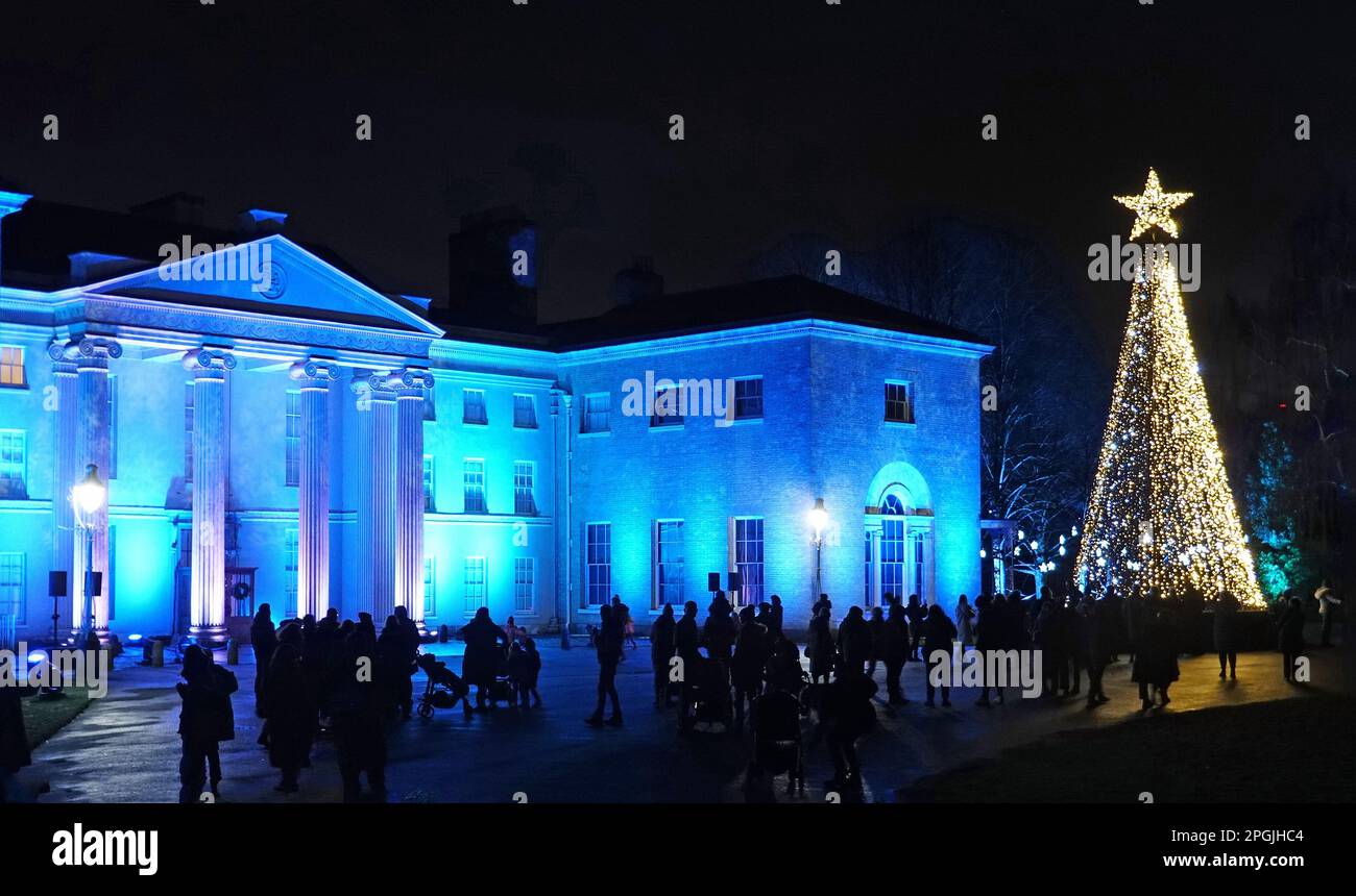 Kenwood House, illuminata per Natale con alti alberi di natale illuminati e visitatori che ammirano la vista Foto Stock