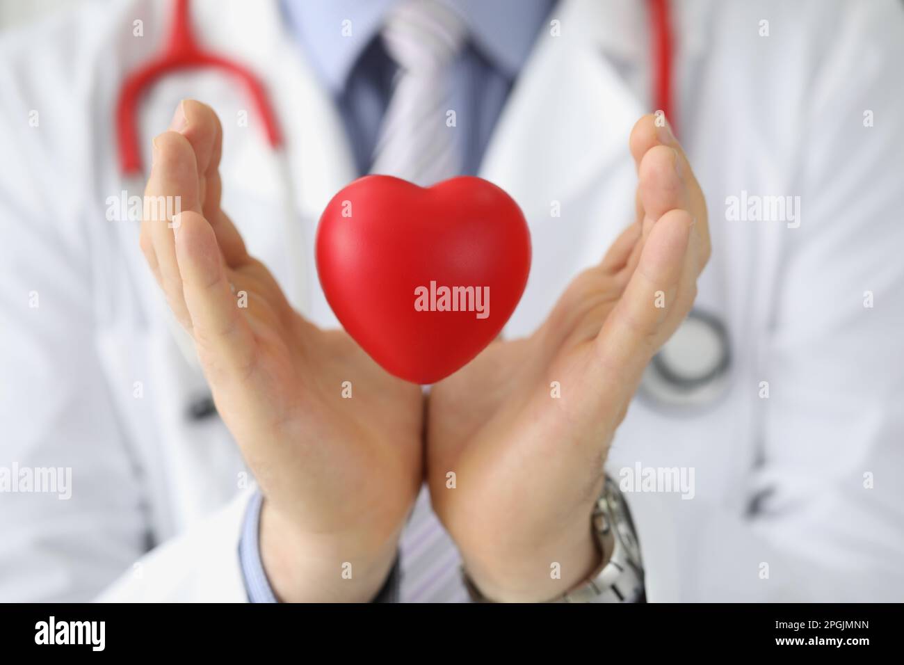 Il cardiologo medico tiene il cuore rosso nell'aria Foto Stock
