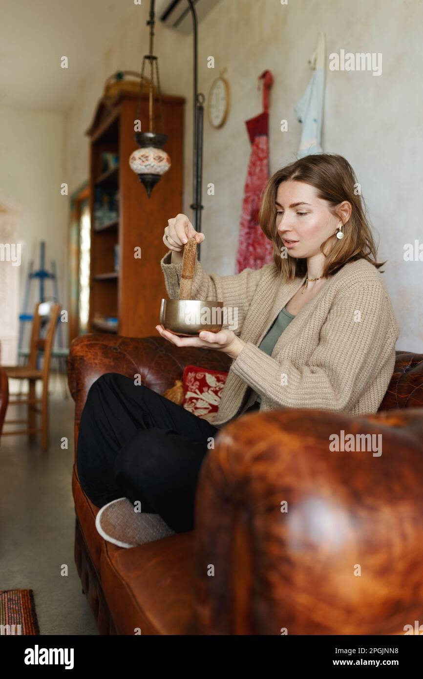 Giovane donna che gioca su un canto tibetano Bowl.Relaxation e meditazione.Sound terapia, medicina alternativa.Buddhista guarigione pratiche.spazio di compensazione di energia negativa.fuoco selettivo, primo piano. Foto Stock