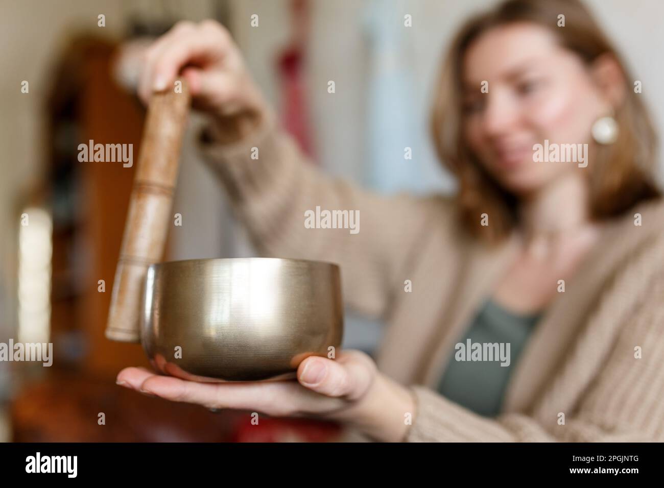 Giovane donna che gioca su un canto tibetano Bowl.Relaxation e meditazione.Sound terapia, medicina alternativa.Buddhista guarigione pratiche.spazio di compensazione di energia negativa.fuoco selettivo, primo piano. Foto Stock