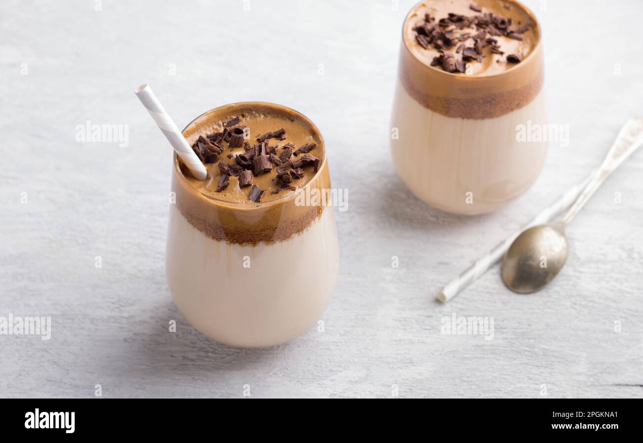 Due bicchieri con caffè Dalgona, cocktail freddo con schiuma di caffè montata cosparsa di scaglie di cioccolato, popolare bevanda di tendenza su una texture leggera Foto Stock