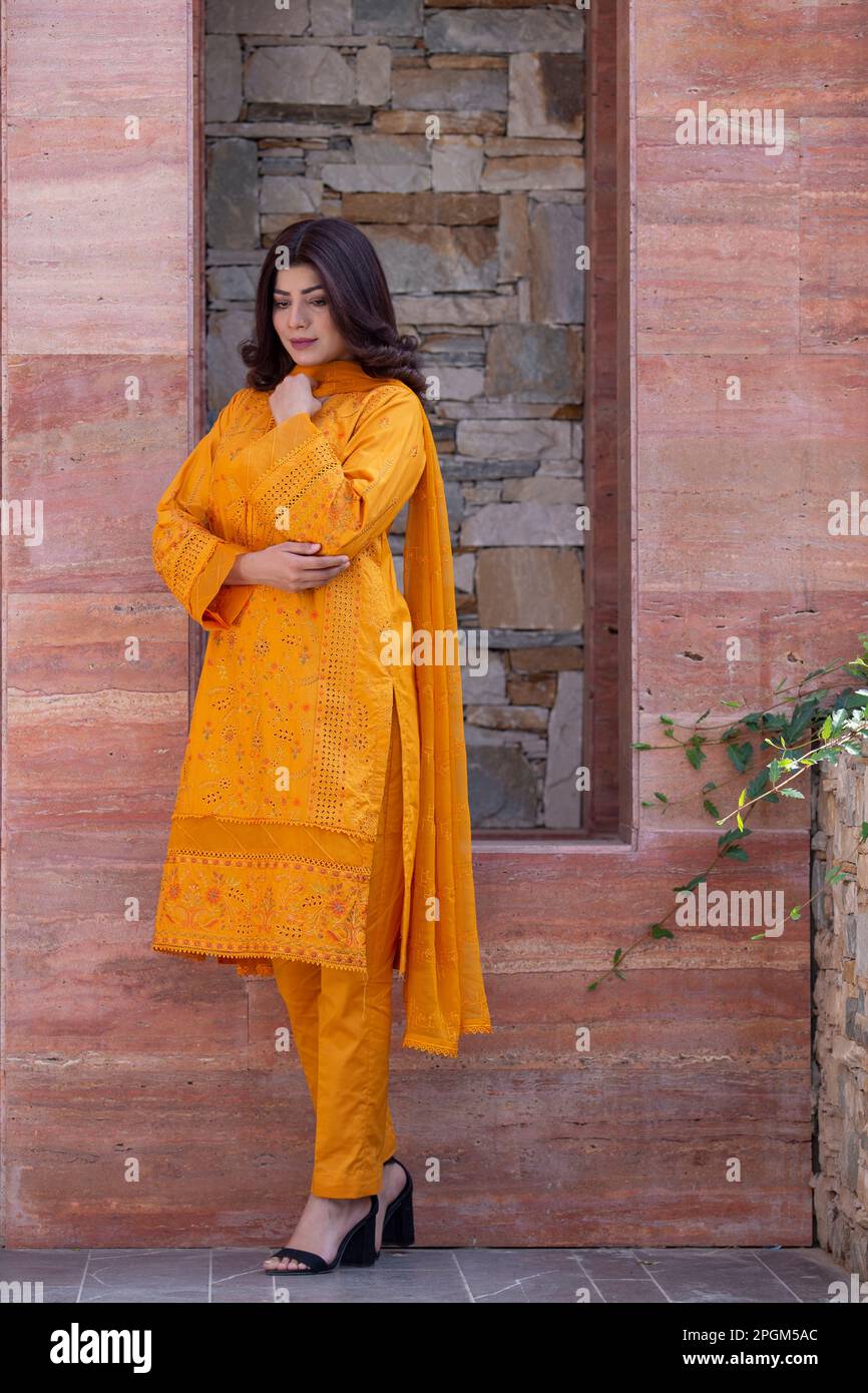 Modello femminile in posa all'aperto indossando arancione indiano pakistano asiatico tradizionale kameez salwar, Foto Stock