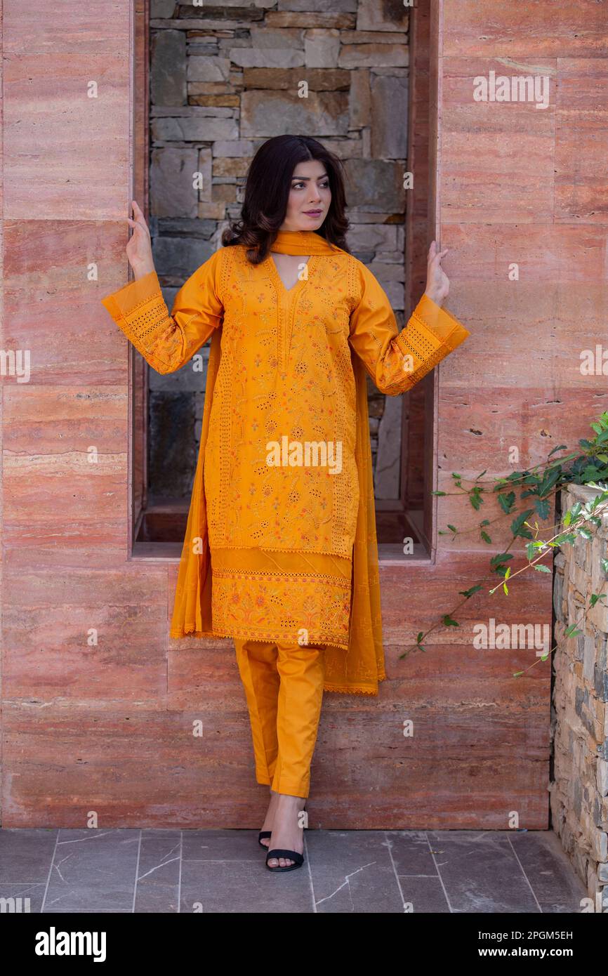 Modello femminile in posa all'aperto indossando arancione indiano pakistano asiatico tradizionale kameez salwar, Foto Stock