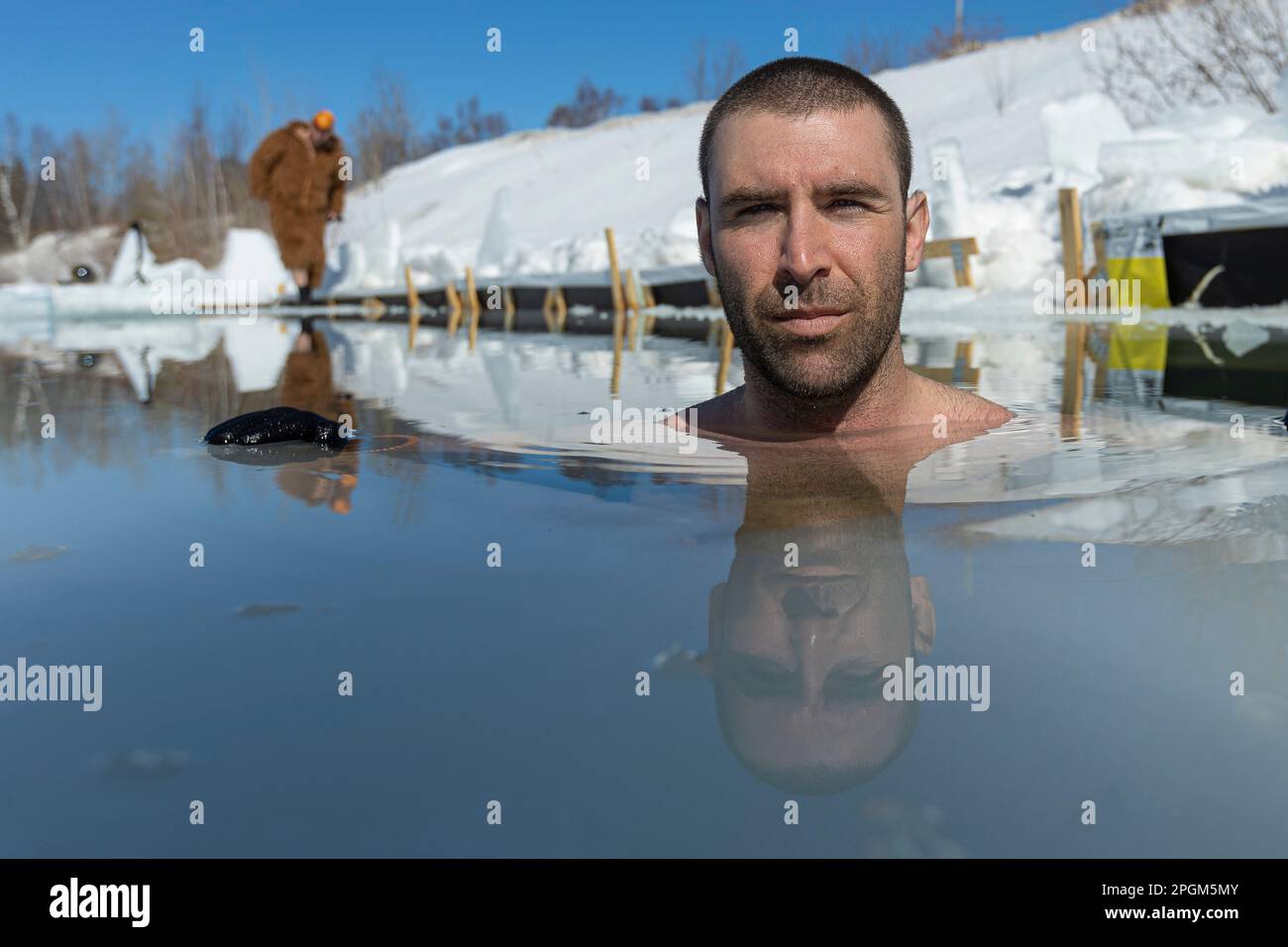 Martin Brunet Rilassati nell'acqua fredda di un lago ghiacciato in un modo divertente a sud di Quebec City il 12 marzo 2023. Foto Stock