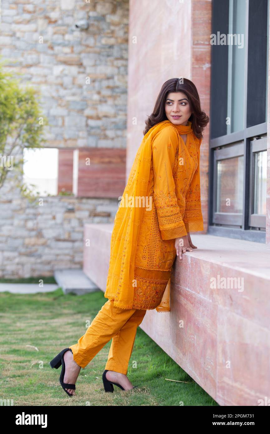 Modello femminile in posa all'aperto indossando arancione indiano pakistano asiatico tradizionale kameez salwar, Foto Stock