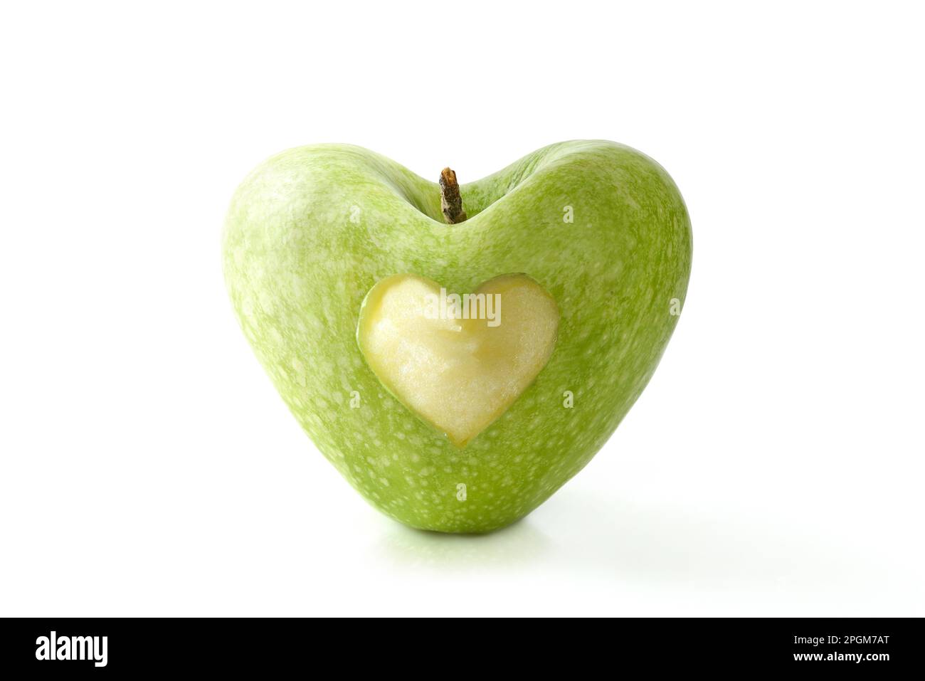 Mela verde a forma di cuore mangiata a metà al centro riflessa su tavola bianca e sfondo bianco isolato. Buona salute, alimentazione e benessere conc Foto Stock