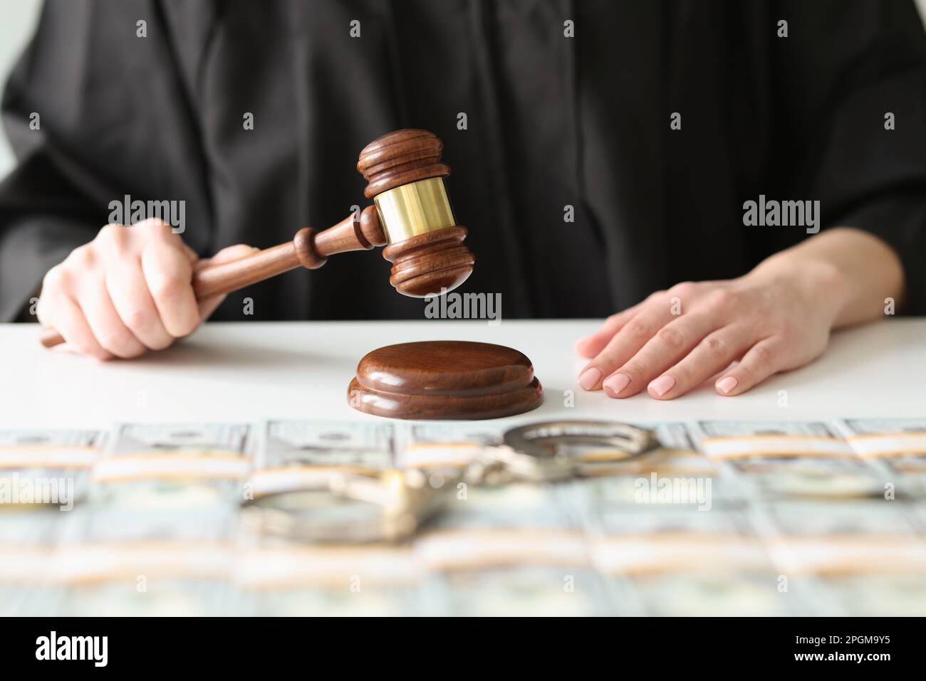 Il giudice femminile bussa con il gavel vicino ai pacchi di dollari Foto Stock