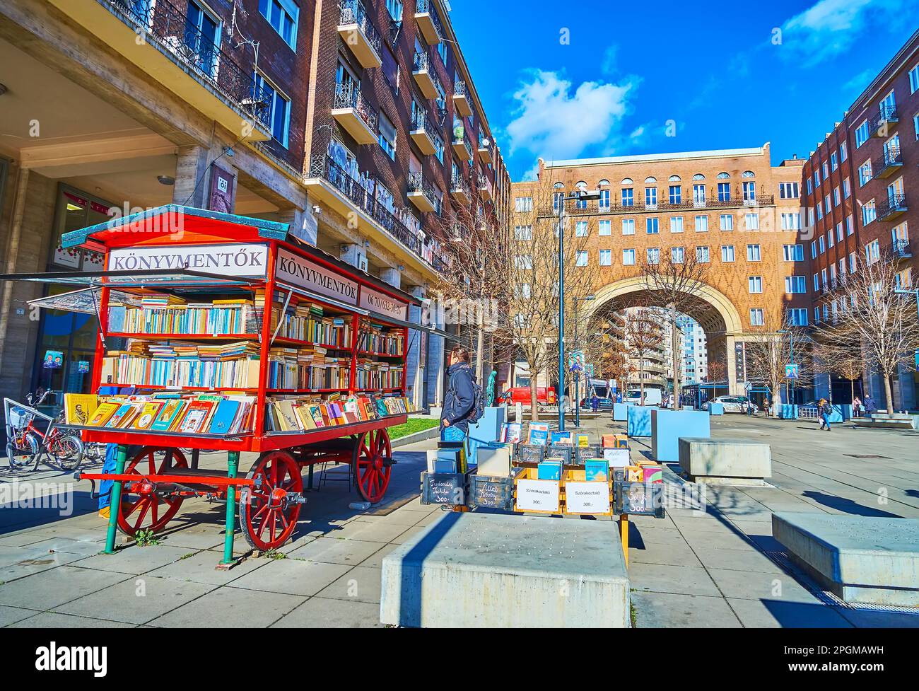 BUDAPEST, UNGHERIA - 22 FEBBRAIO 2022: Il chiosco di libri in stile vintage su Piazza Imre Maach con case di Madach in mattoni rossi con alto colonnato e passo ad arco Foto Stock