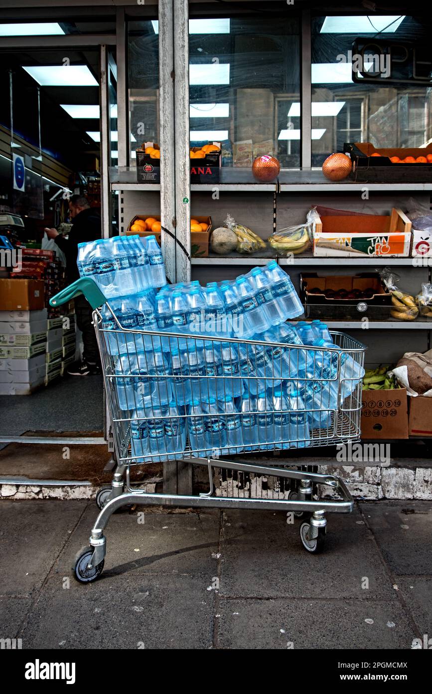 Il carrello per lo shopping è accatastato con acqua in bottiglia fuori da un minimarket asiatico in Nicolson Street, Edimburgo, Scozia, Regno Unito. Foto Stock