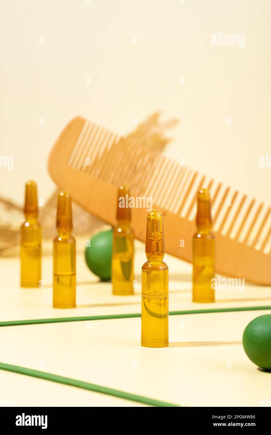 Fotografia moderna e creativa. Ampolle cosmetiche con siero per la crescita dei capelli, restauro.pettine, puntine verdi su sfondo beige.concetto di bellezza h Foto Stock