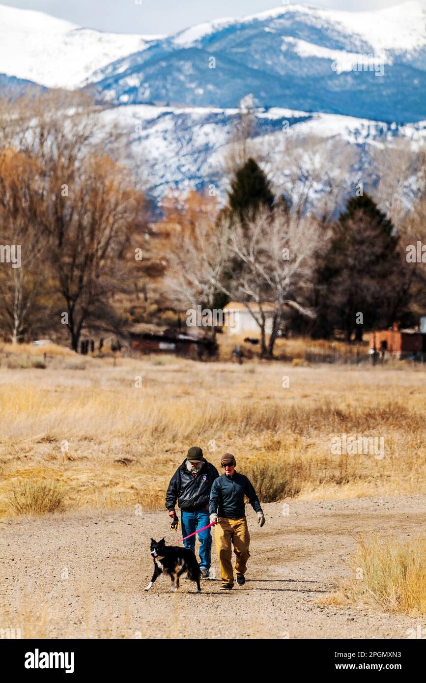Due uomini adulti che camminano il loro cane sulla strada sterrata rurale; Vandaveer Ranch; Salida; Colorado; USA Foto Stock