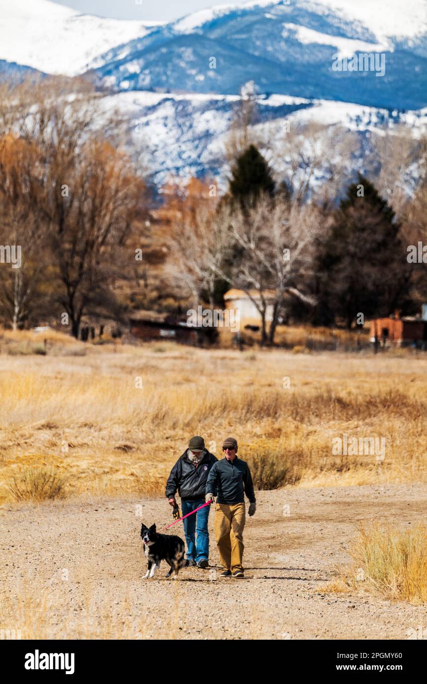 Due uomini adulti che camminano il loro cane sulla strada sterrata rurale; Vandaveer Ranch; Salida; Colorado; USA Foto Stock