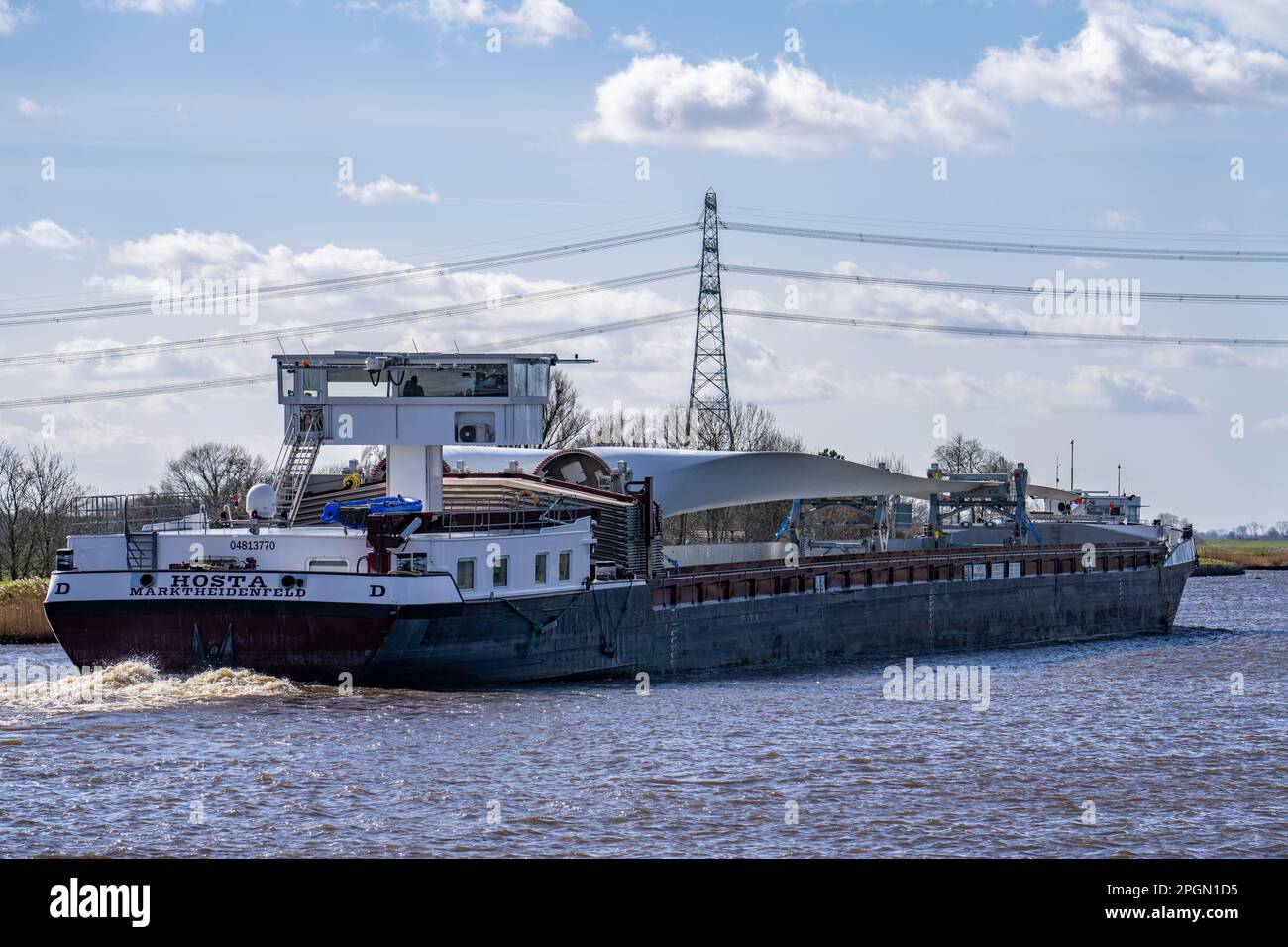 Trasporto di rotori, pale per turbine eoliche, da parte di un aereo da terra sui canali dei Paesi Bassi, vicino a Groningen, dal produttore all'assemblaggio in loco Foto Stock