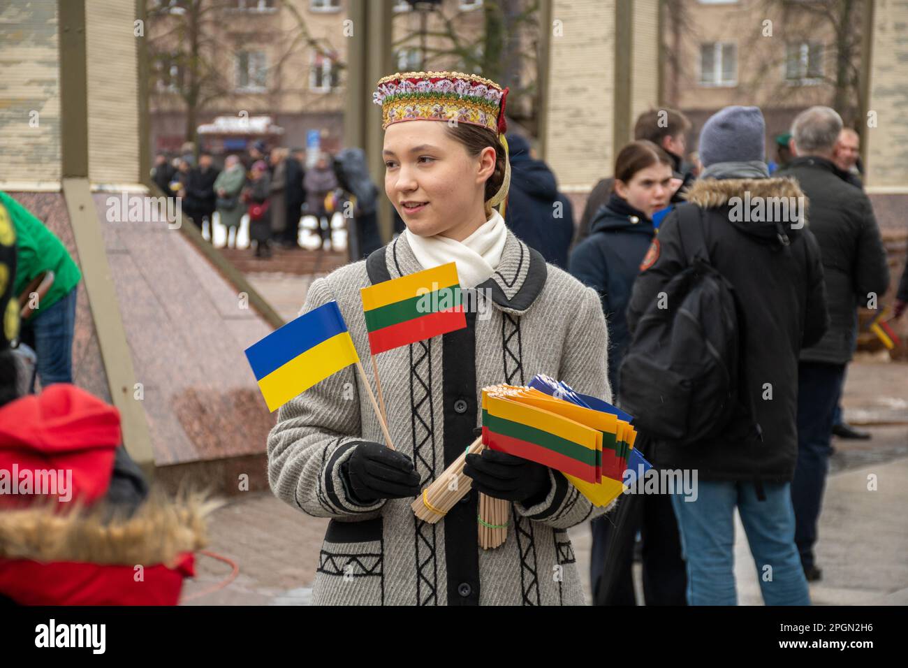 Vilnius Lituania - Marzo 11 2023: Bella ragazza lituana in costume tradizionale con bandiere lituane e ucraine durante una cerimonia Foto Stock
