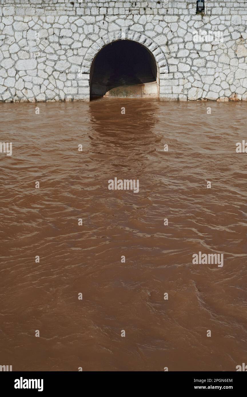 acqua marrone in un fiume indietro fatto di mattoni e un tunnel Foto Stock