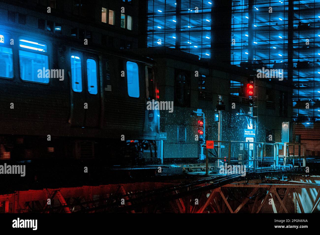 Una luce blu brillante illumina un treno CTA che si muove costantemente lungo un paio di binari ferroviari Foto Stock