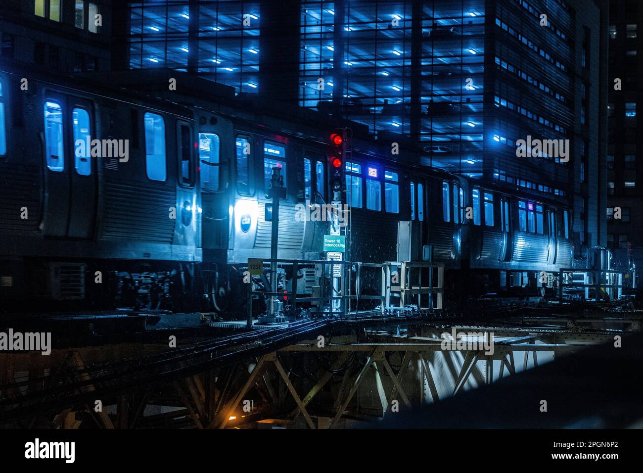 Un treno sui binari di notte, illuminato da un'unica luce rossa Foto Stock