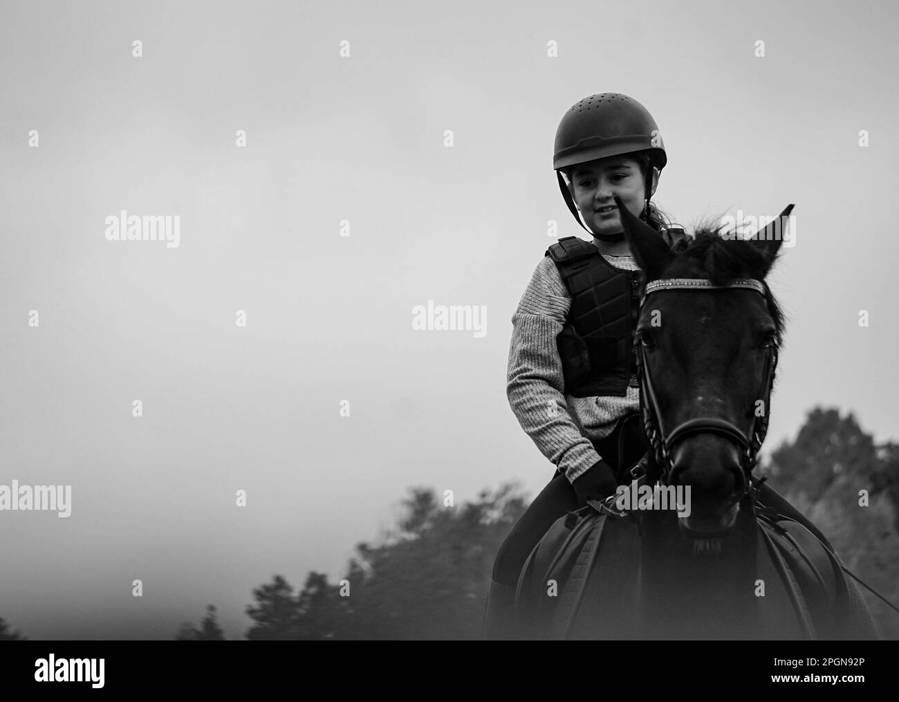 Una ragazza che cavalca un cavallo contro il cielo Foto Stock
