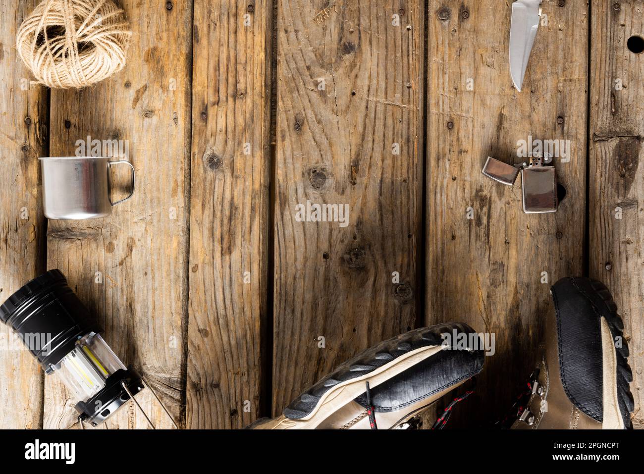 Attrezzatura da campeggio di coltello tascabile, scarpe da trekking e lampada su sfondo in legno con spazio copia Foto Stock