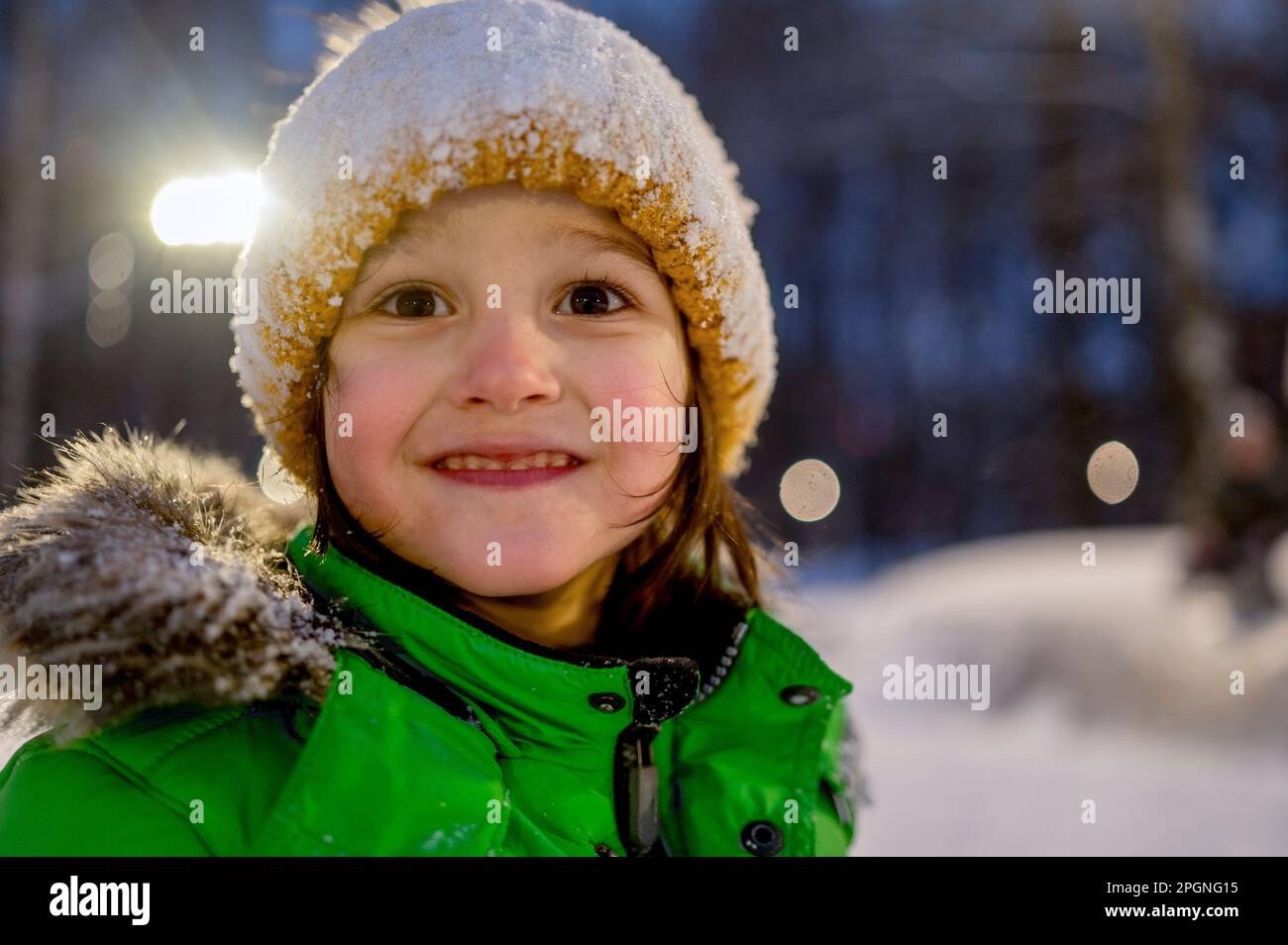 Ragazzo carino che indossa un cappello a maglia coperto di neve di notte Foto Stock