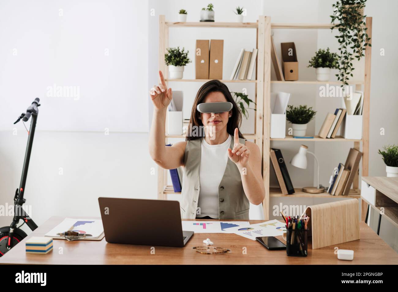 Donna d'affari che indossa occhiali VR seduti alla scrivania in ufficio Foto Stock