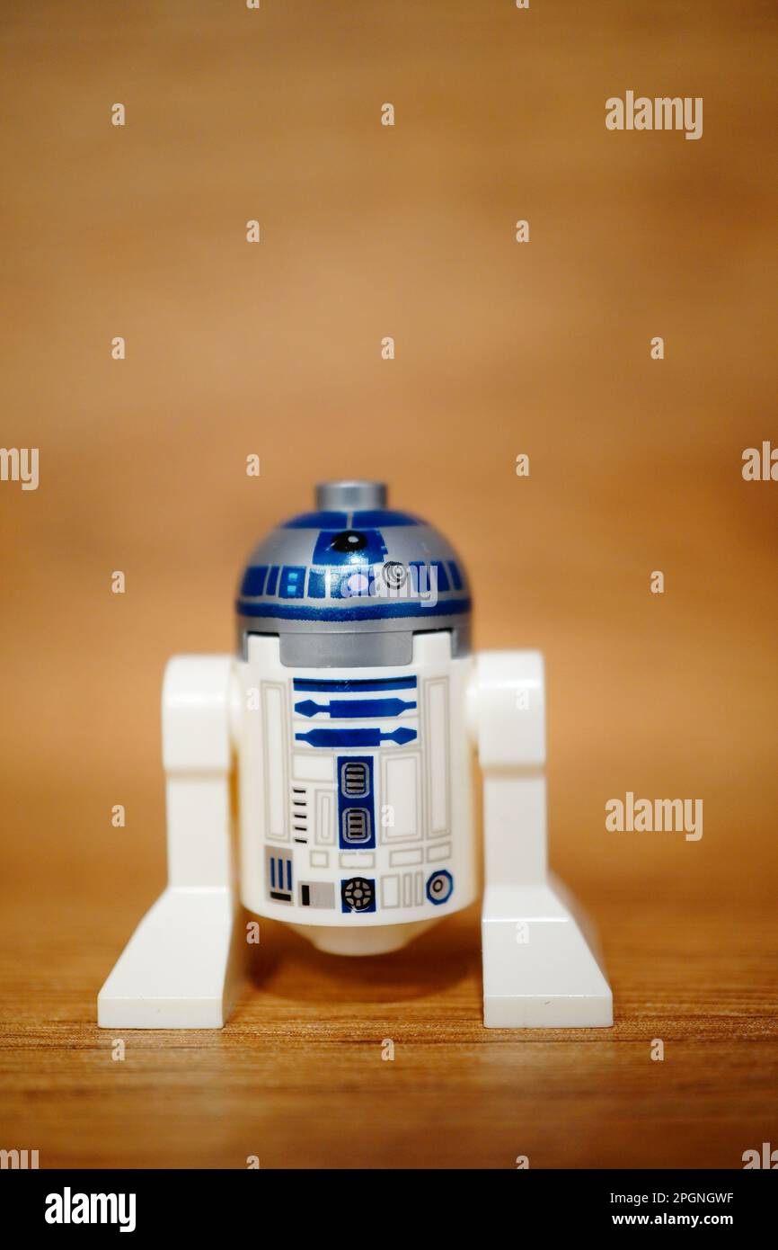 Una figura LEGO Star Wars R2D2 sopra un tavolo di legno, il suo corpo blu e bianco illuminato dalla luce calda della stanza Foto Stock